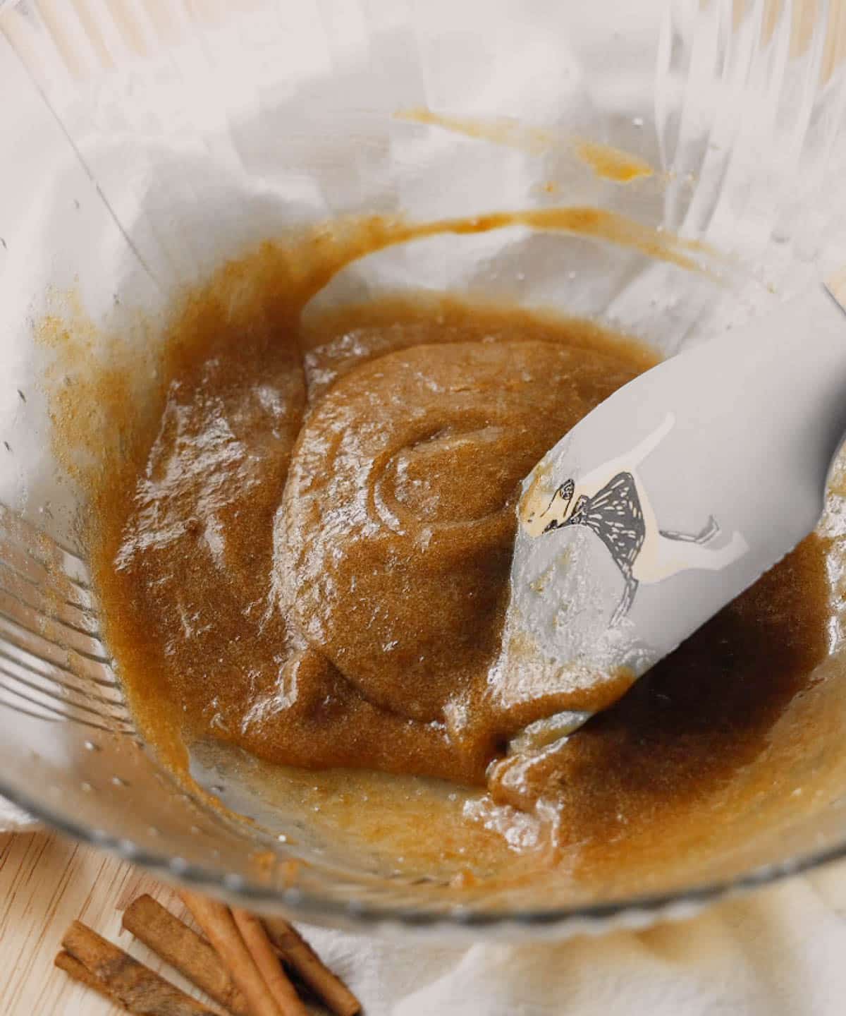 Brown batter of most wet ingredients in glass mixing bowl.