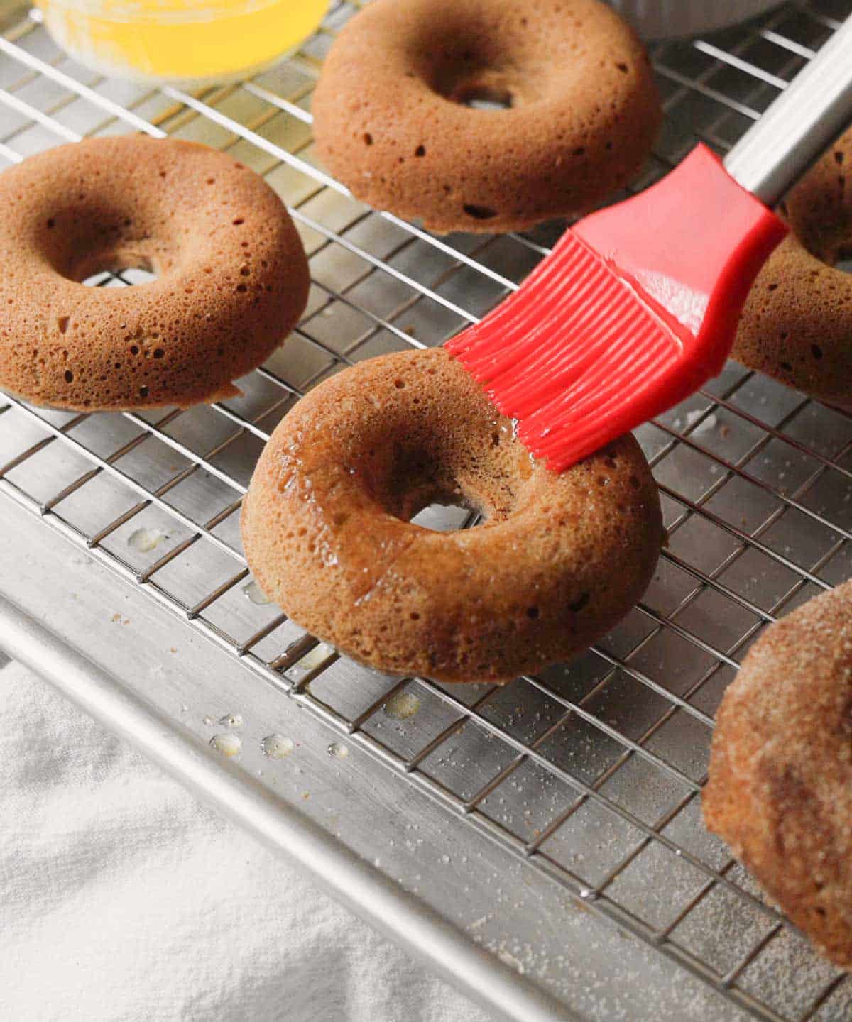 Brushing baked mochi donut with melted butter.