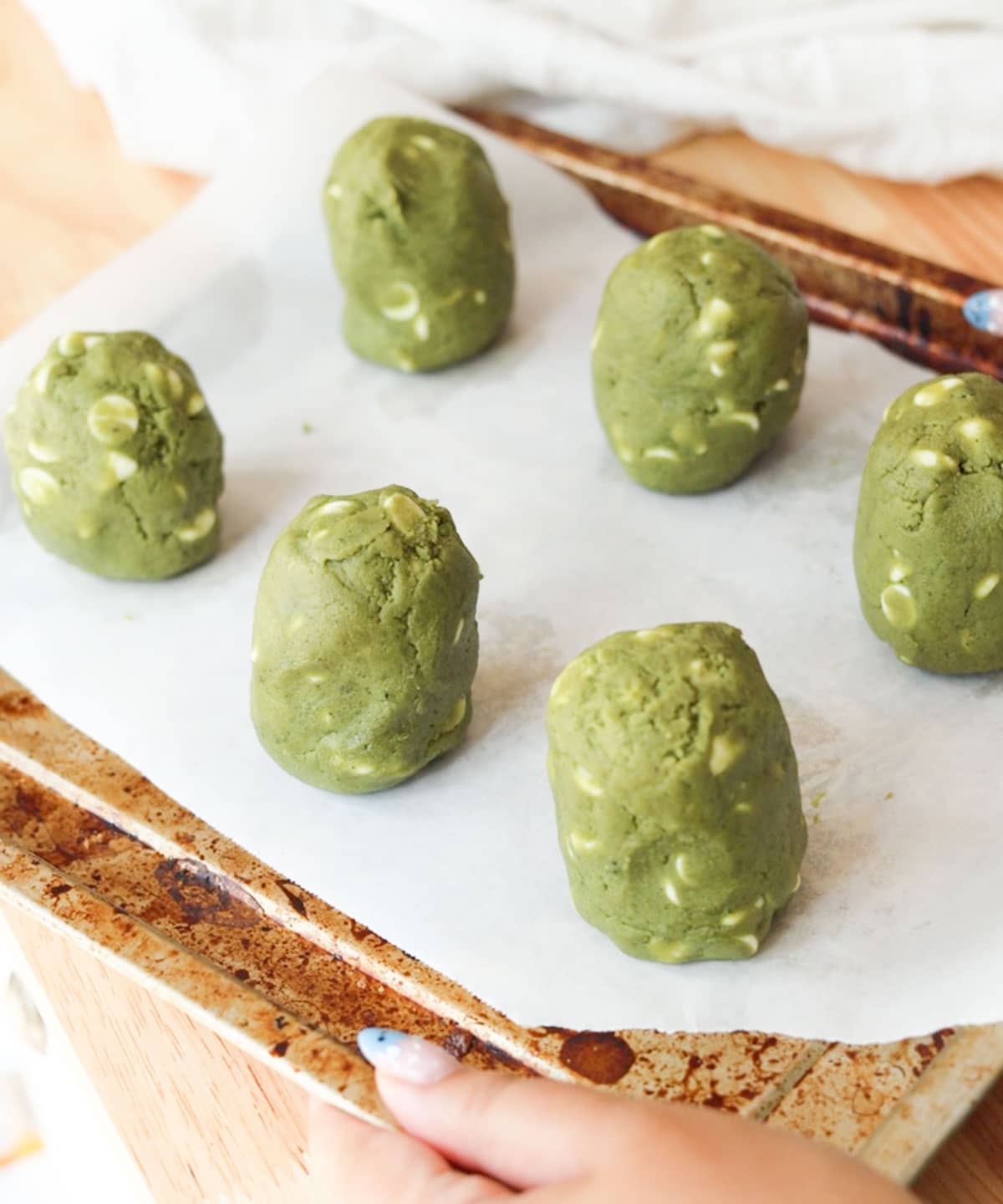 6 tall mounds of matcha cookie dough on a lined tray.