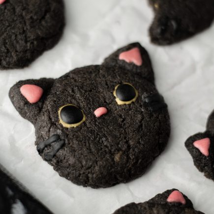 Black cocoa cat cookies on parchment paper.