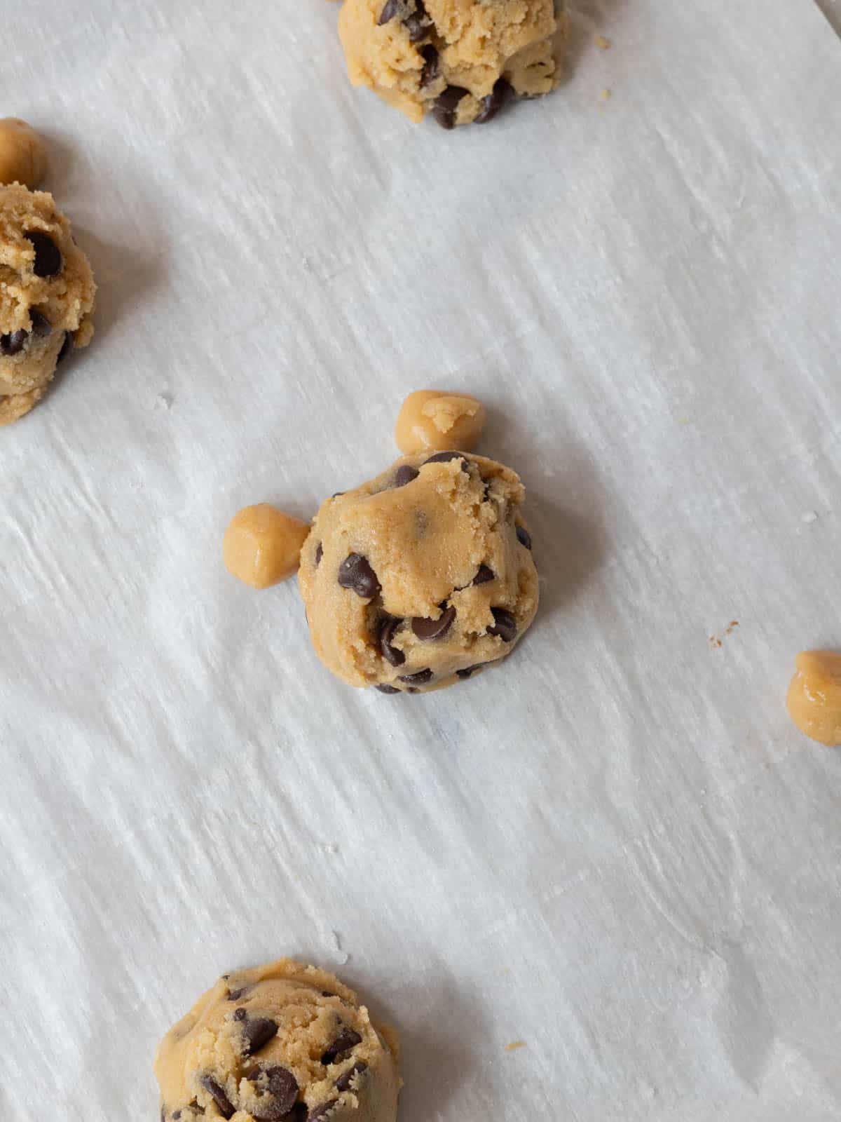 Teddy bear cookie dough balls on lined baking tray ready to be baked.