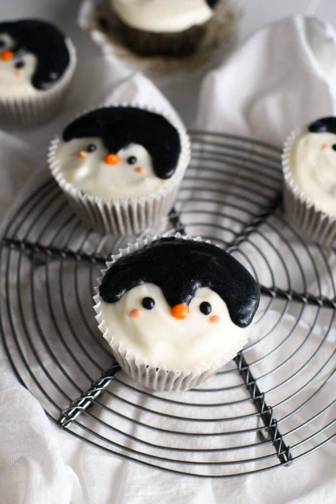 Penguin cupcakes on a wire rack.