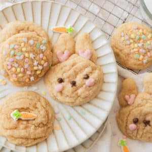 Cute bunny sugar cookie next to other cookies with a decorative carrot sprinkle or pastel sprinkles.