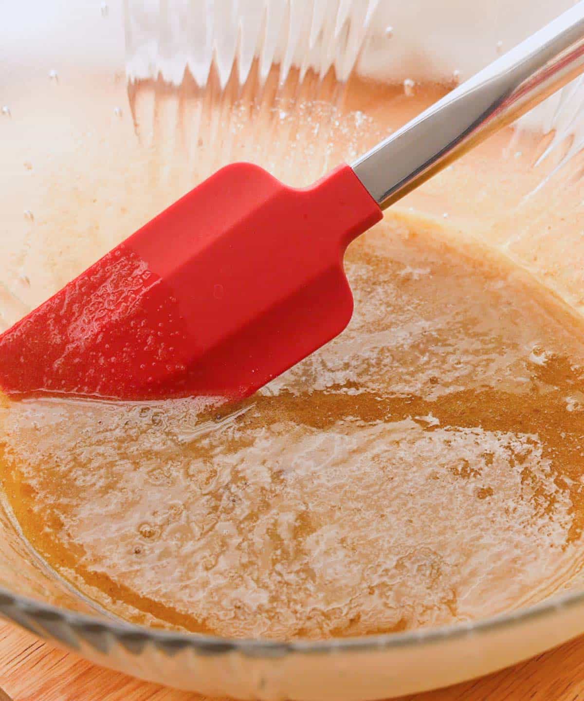 Melted butter and sugars mixed in a glass mixing bowl.