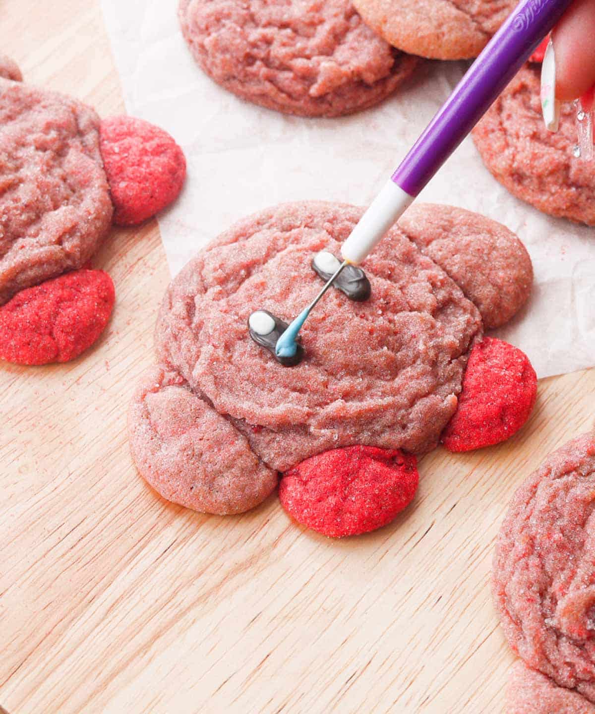 Using a scribe to add chocolate decorations on Kirby cookie's face.