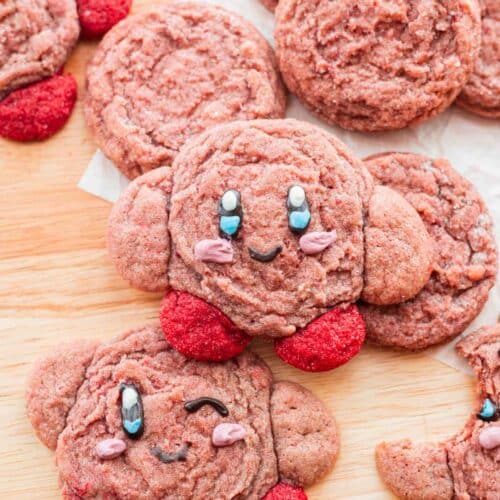 Strawberry kirby cookies spread out on a wooden island.