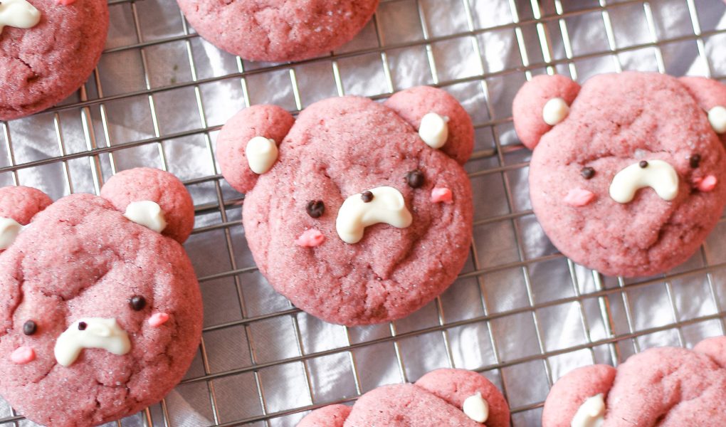 Pink strawberry bear cookies on a wire rack