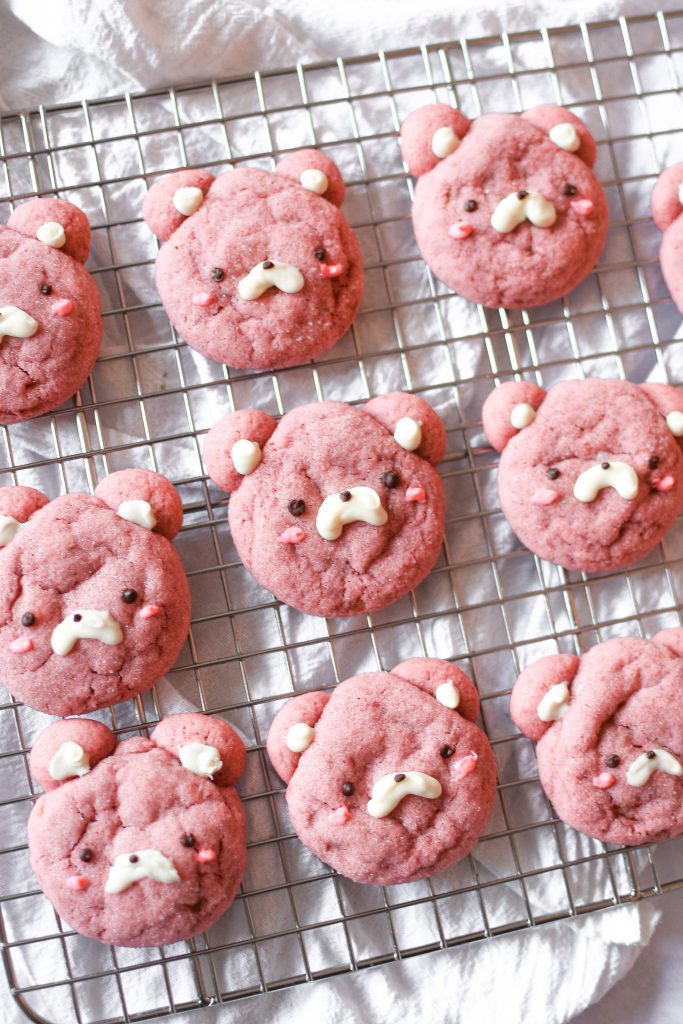 Pink strawberry bear cookies on a wire rack