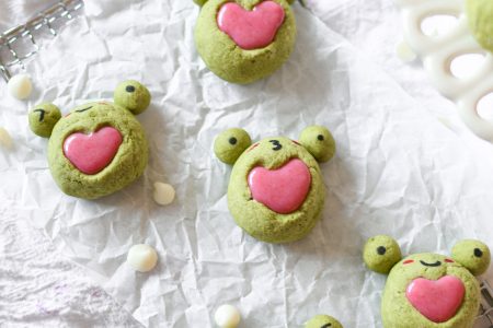 Frog matcha heart thumbprint cookies with strawberry ganache on a rectangular wire rack