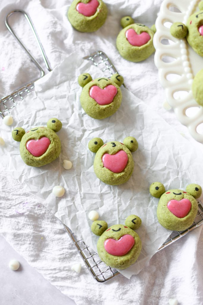 Frog matcha heart thumbprint cookies with strawberry ganache on a rectangular wire rack