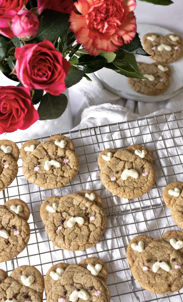 Brown butter espresso bear cookies on a wire rack next to a vase of flowers