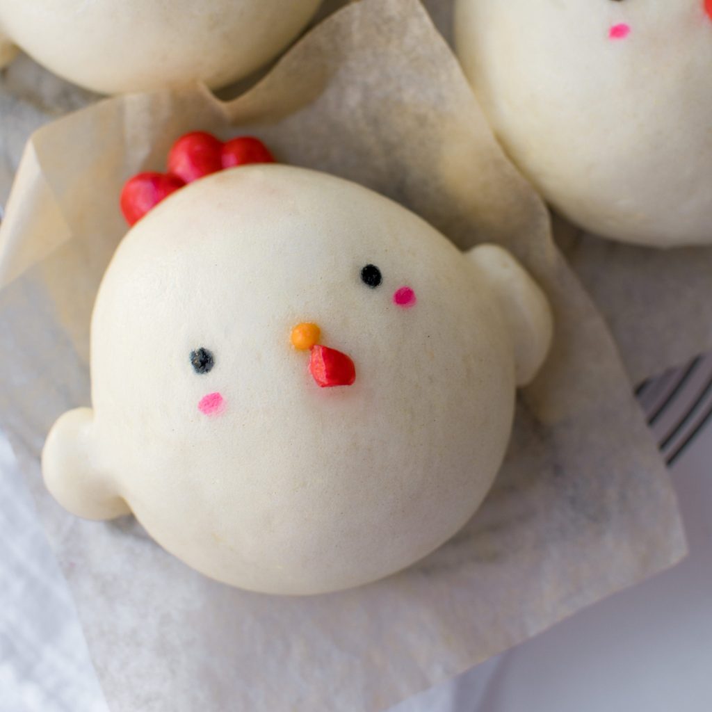 Chicken-shaped steamed bun on parchment paper.