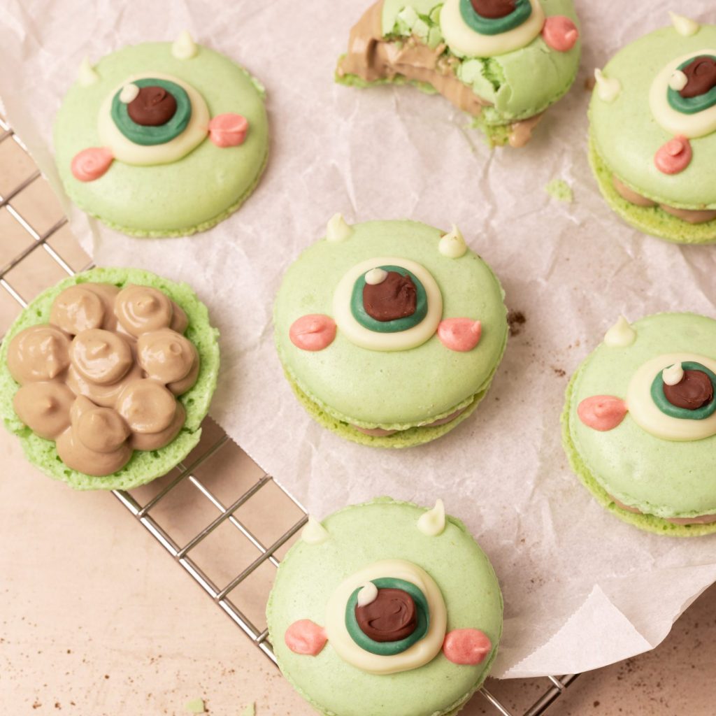 Mike Wazowski macarons on parchment paper on a wire rack.