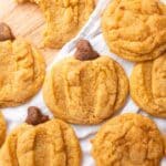 Pumpkin snickerdoodles shaped as pumpkins on a wooden backdrop with white linen.