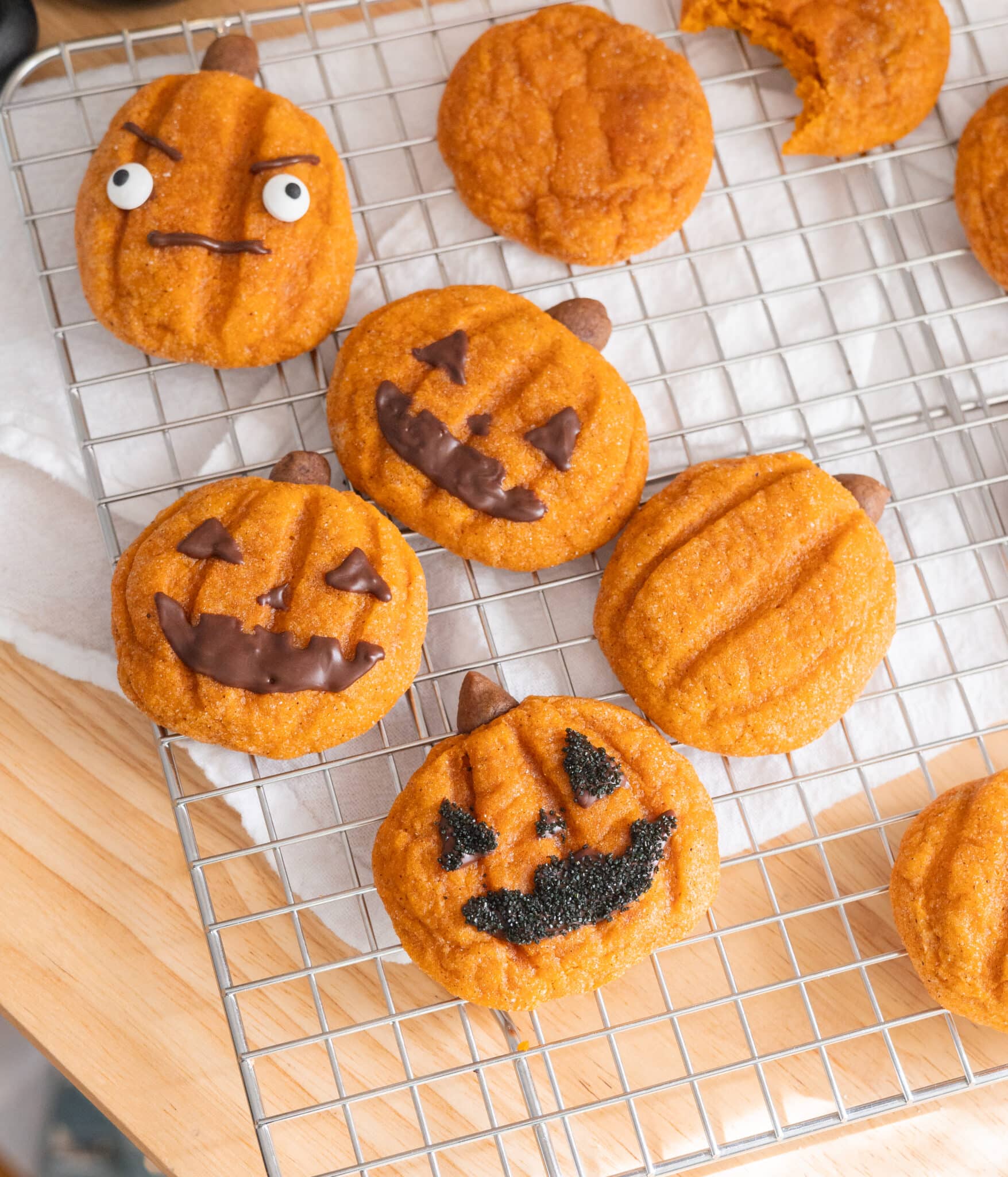 Cute jack o'lantern pumpkin snickerdoodles on a wire rack.