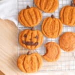 Cute egg-free pumpkin snickerdoodles decorated as jack o'lanterns on a wire rack.