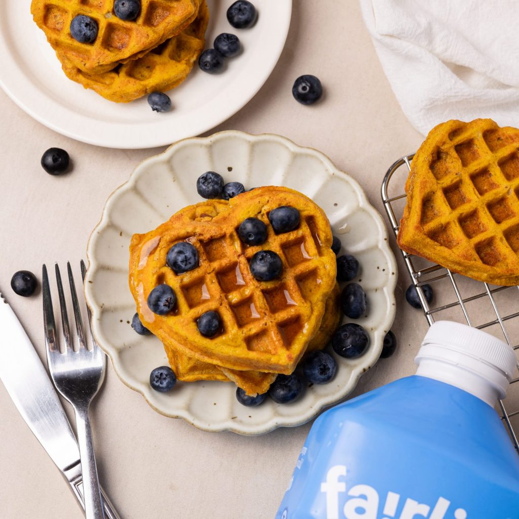 heart shaped mochiko waffles topped with maple syrup and blueberries