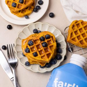 heart shaped mochiko waffles topped with maple syrup and blueberries