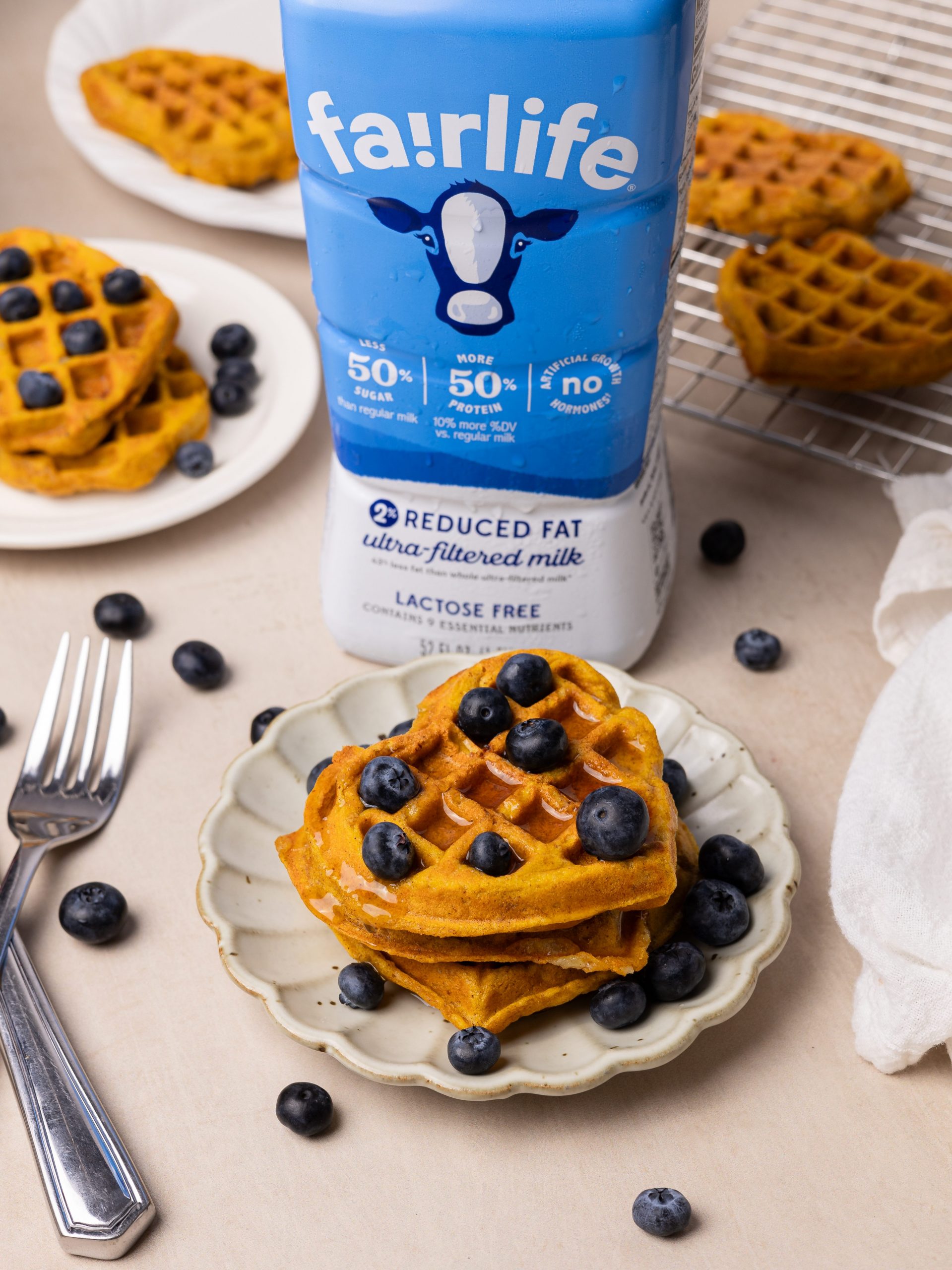 heart-shaped pumpkin mochiko waffles topped with maple syrup and blueberries