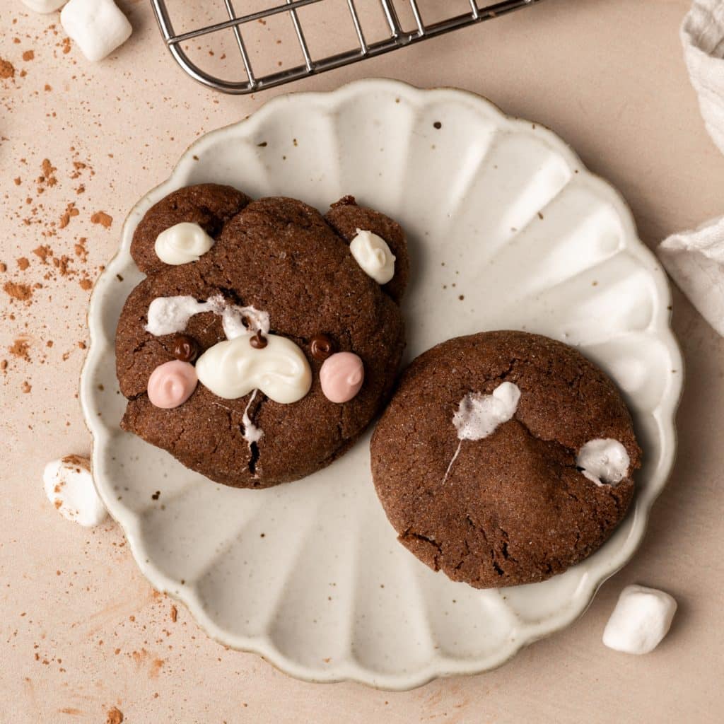 Hot cocoa cookies on a scalloped plate. One looks like a cute bear.