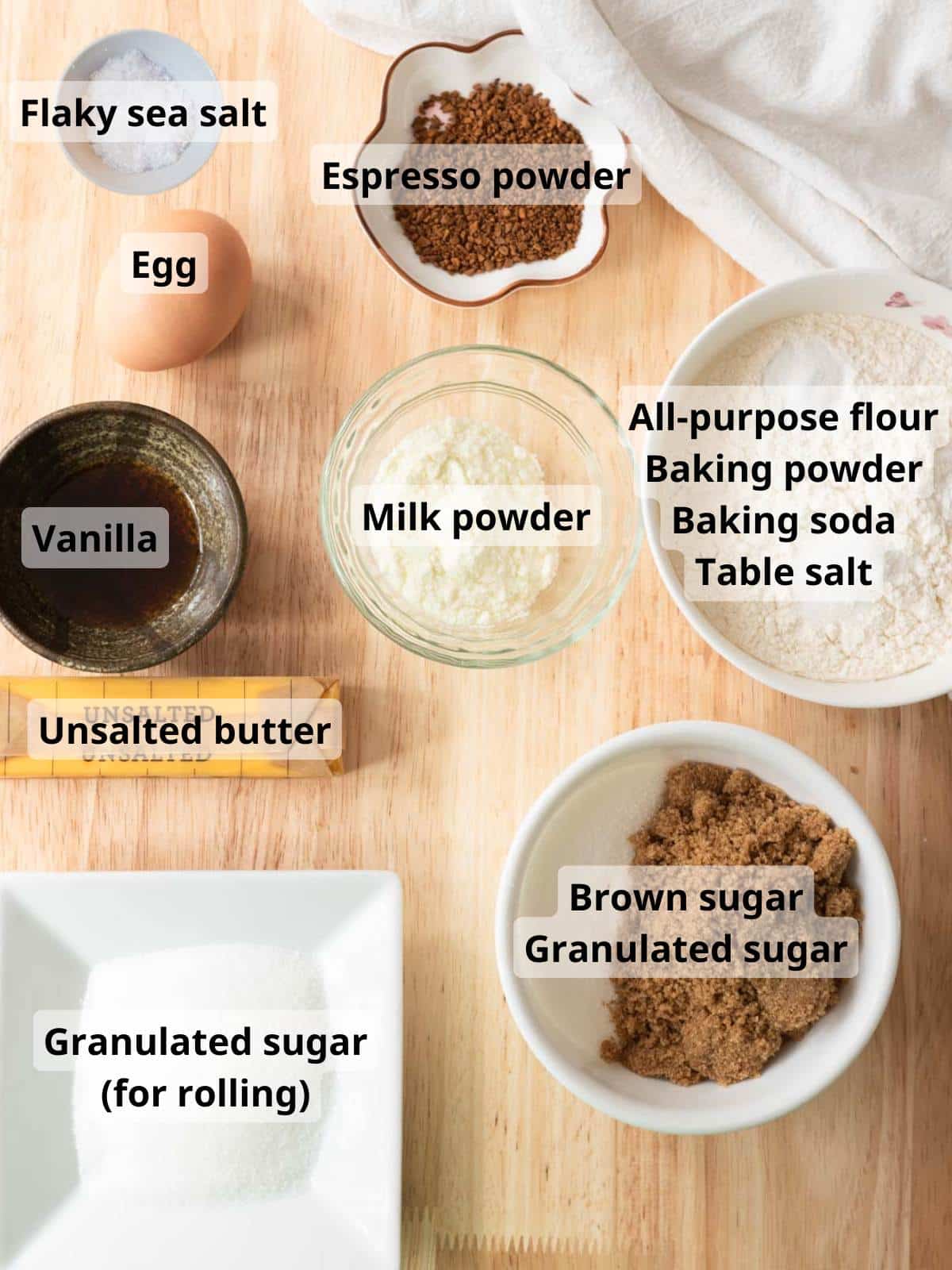 Cookie ingredients laid out on a wooden table, with labels for each ingredient.