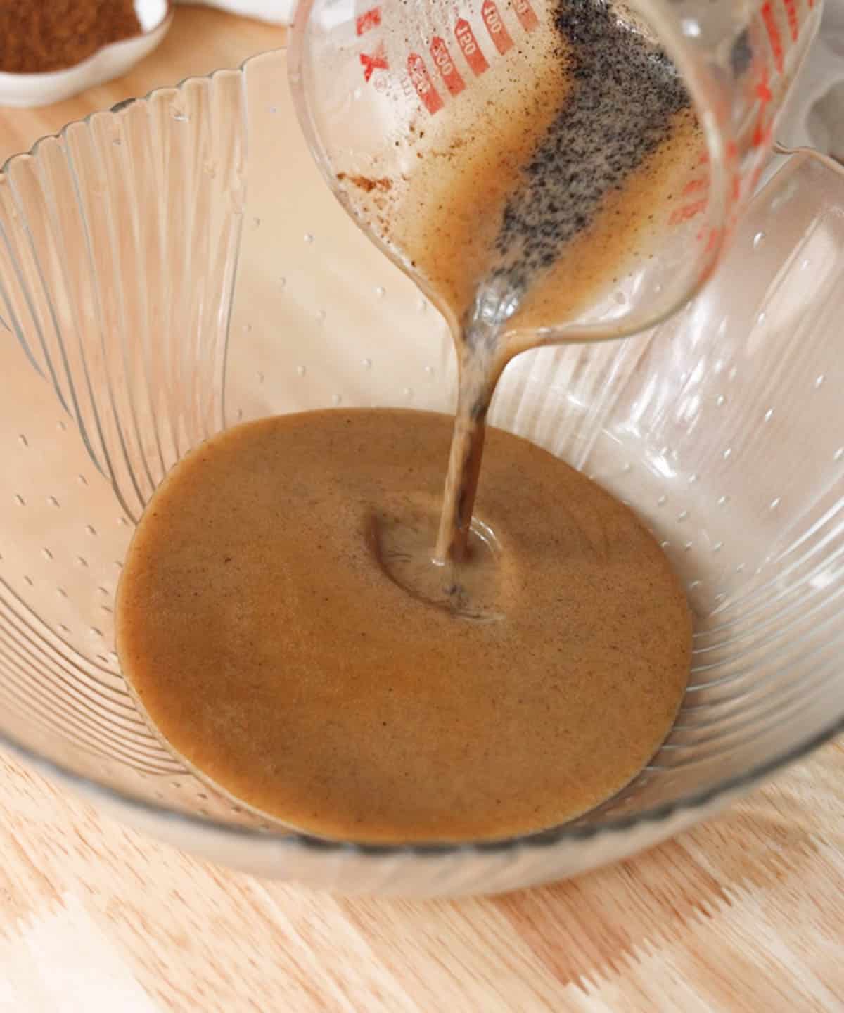 Pouring brown butter, toasted milk powder, and espresso powder into a glass mixing bowl.