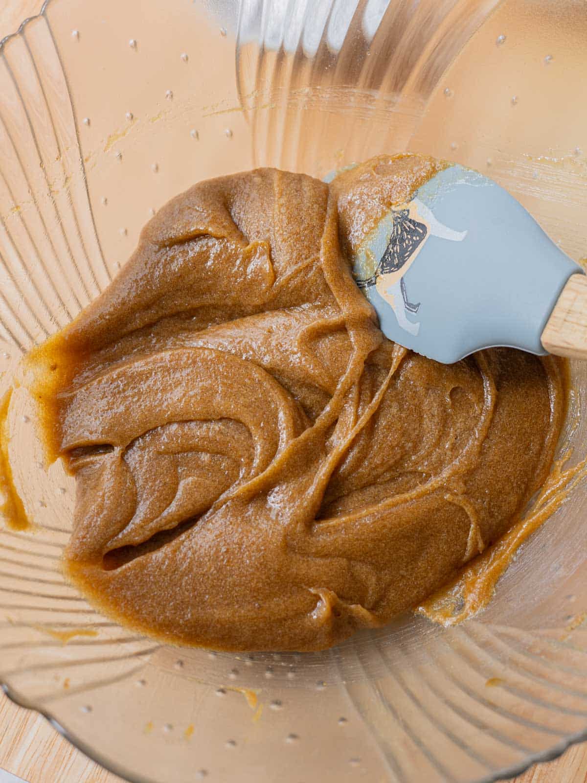 Glass mixing bowl with wet ingredients stirred together.