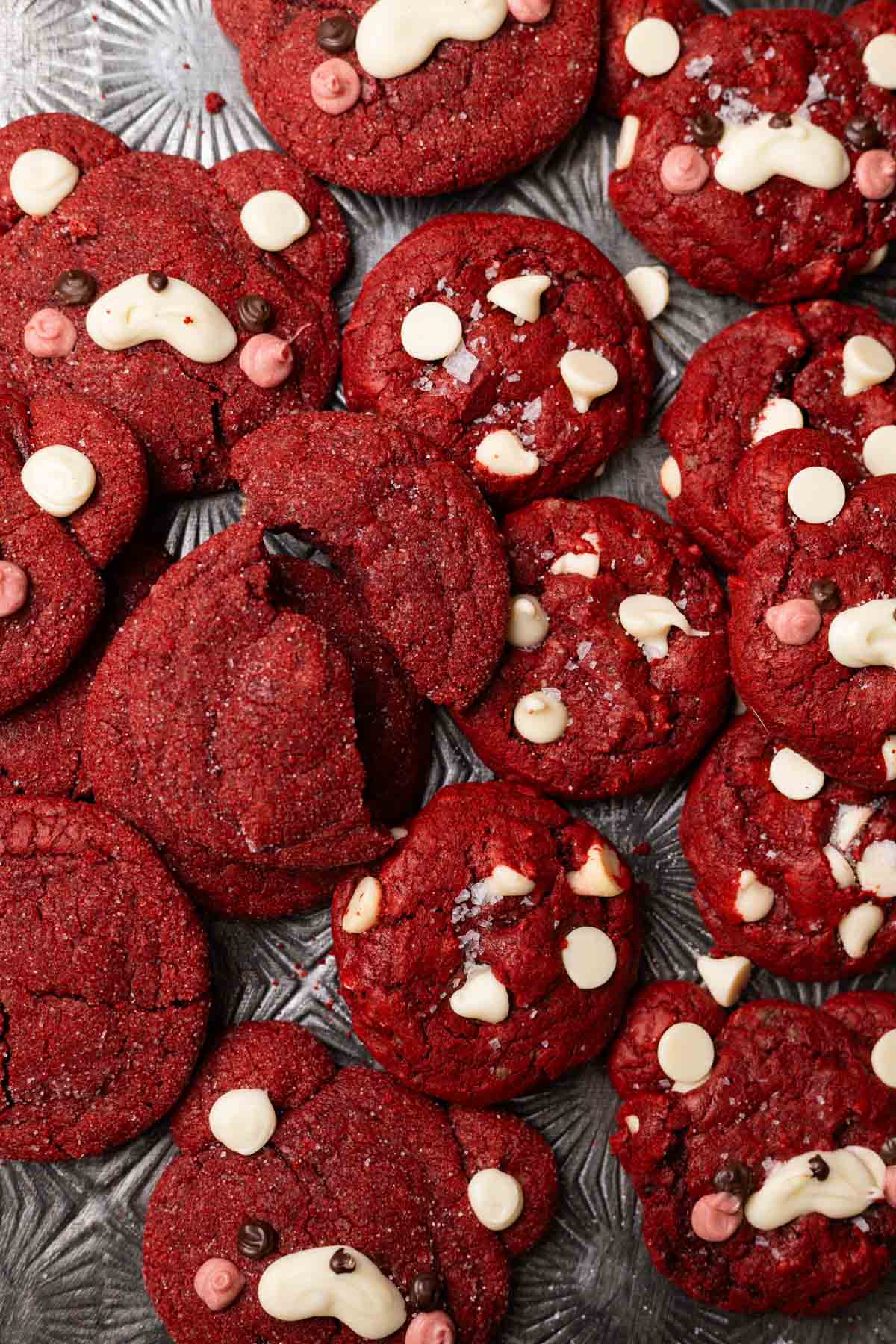 Red velvet sugar cookies and white chocolate red velvet cookies on baking pan.