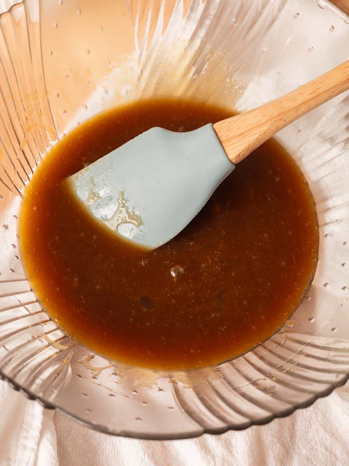 Glass mixing bowl with butter and sugars already combined.