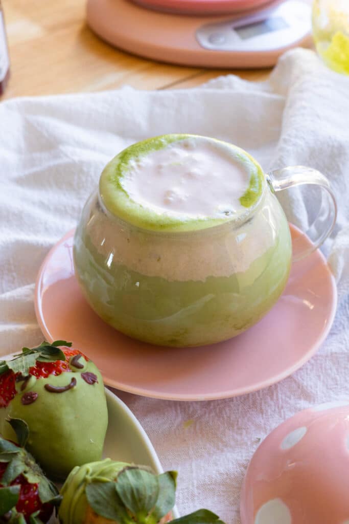 Strawberry matcha latte next to matcha covered strawberries decorated as frogs.