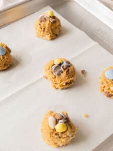 Cookie dough ball on baking tray with crushed Cadbury eggs on top.