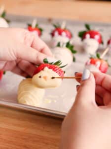 Drawing chick faces on a strawberry with a toothpick dipped in melted chocolate.