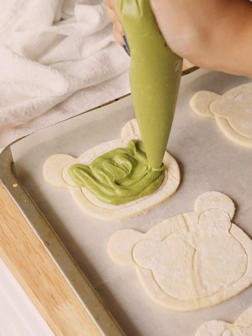 Piping matcha filling to puff pastry.