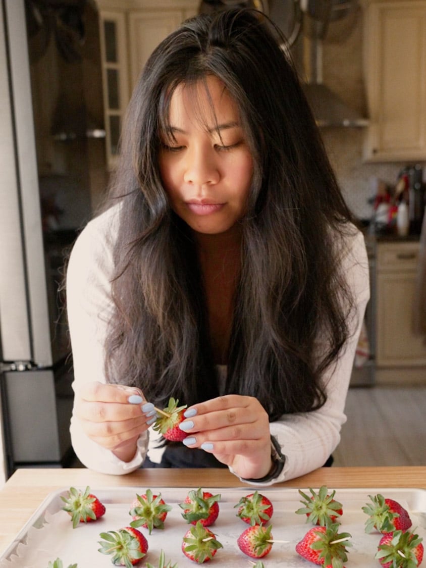 Bianca is skewering strawberries with a toothpick.