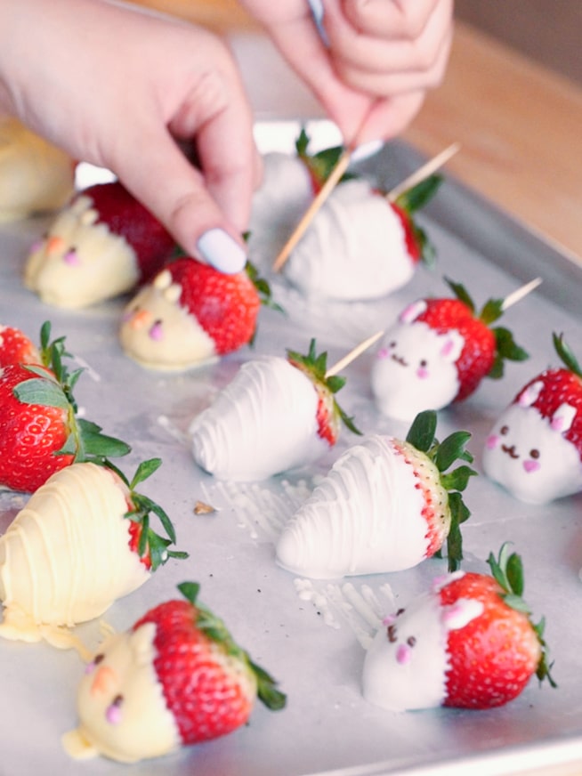 Removing toothpicks from skewered chocolate-dipped strawberries.