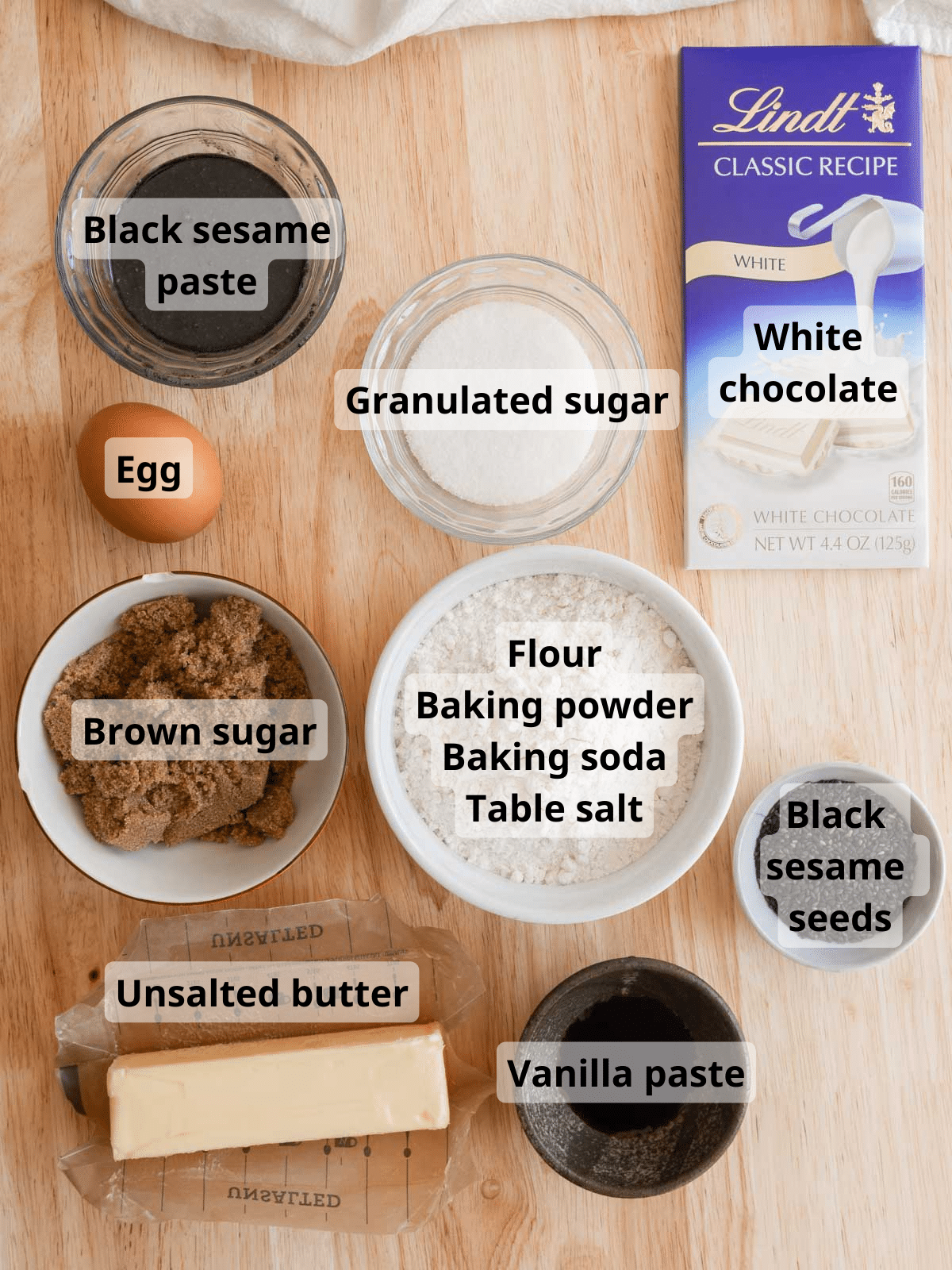 All black sesame cookie ingredients laid out on a wooden backdrop table.