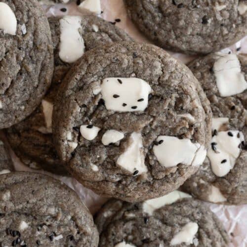 Black sesame cookies with white chocolate chunks layered on top of one another.