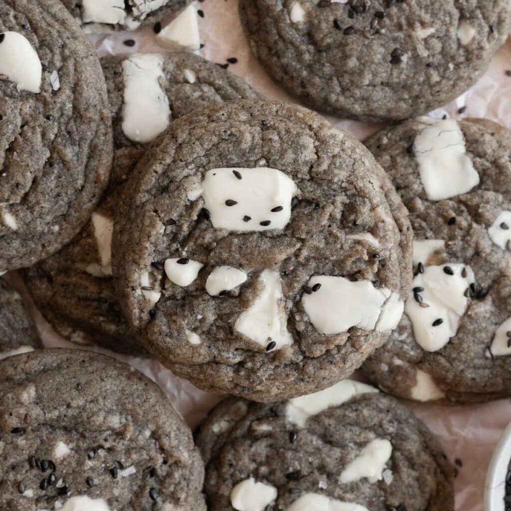 Black sesame cookies with white chocolate chunks layered on top of one another.