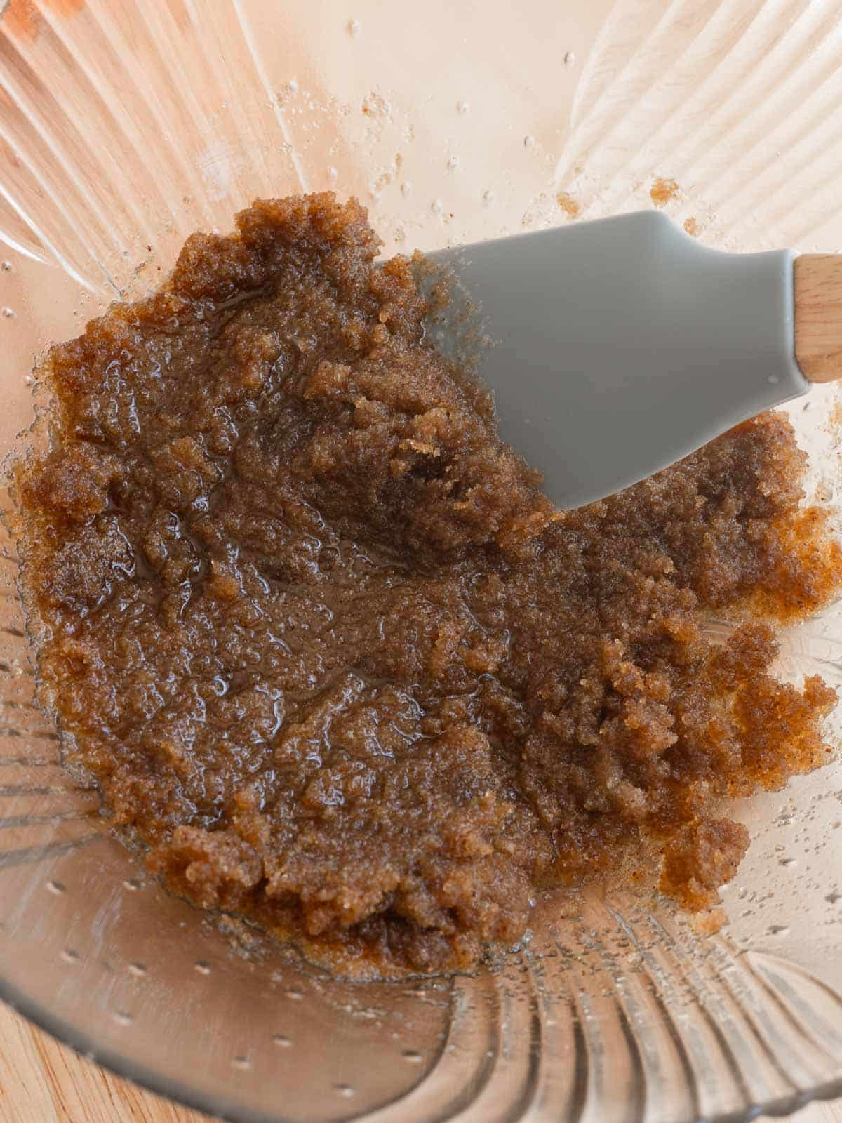 Brown butter mixed with sugars in glass mixing bowl.