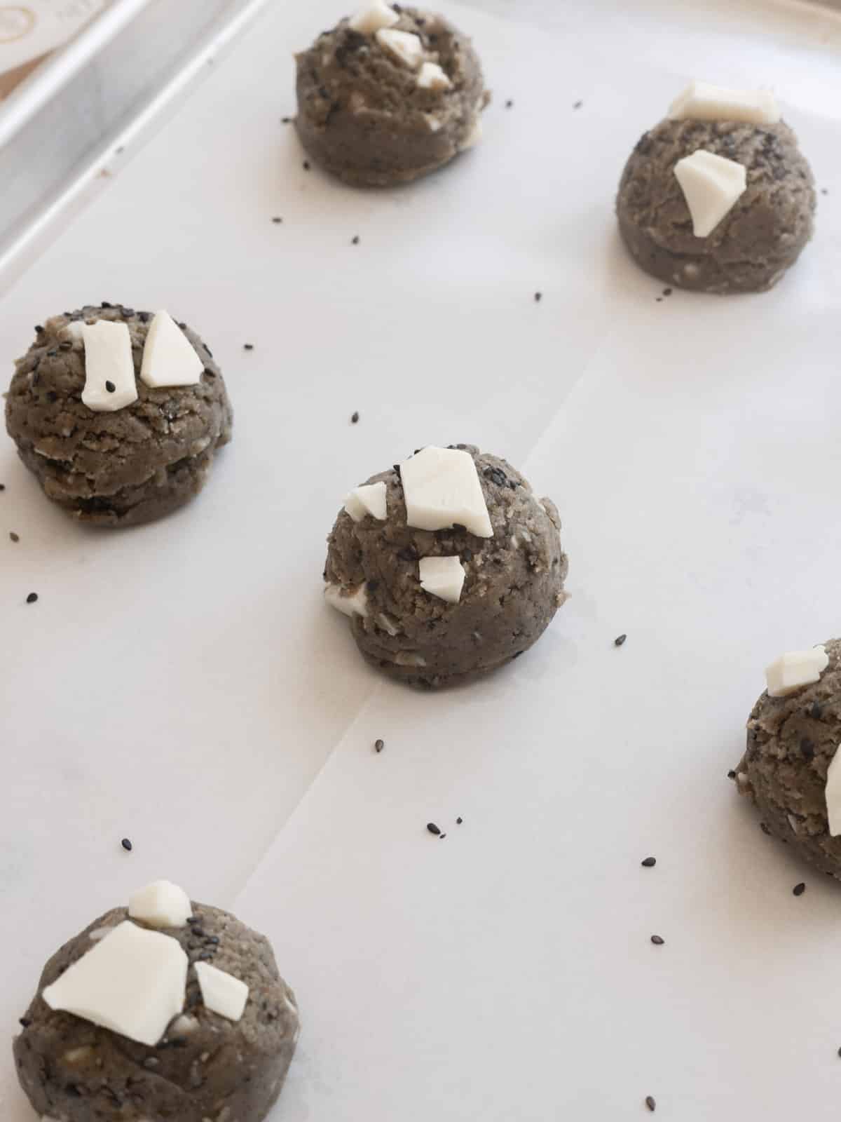 Black sesame cookie dough balls on lined baking tray.