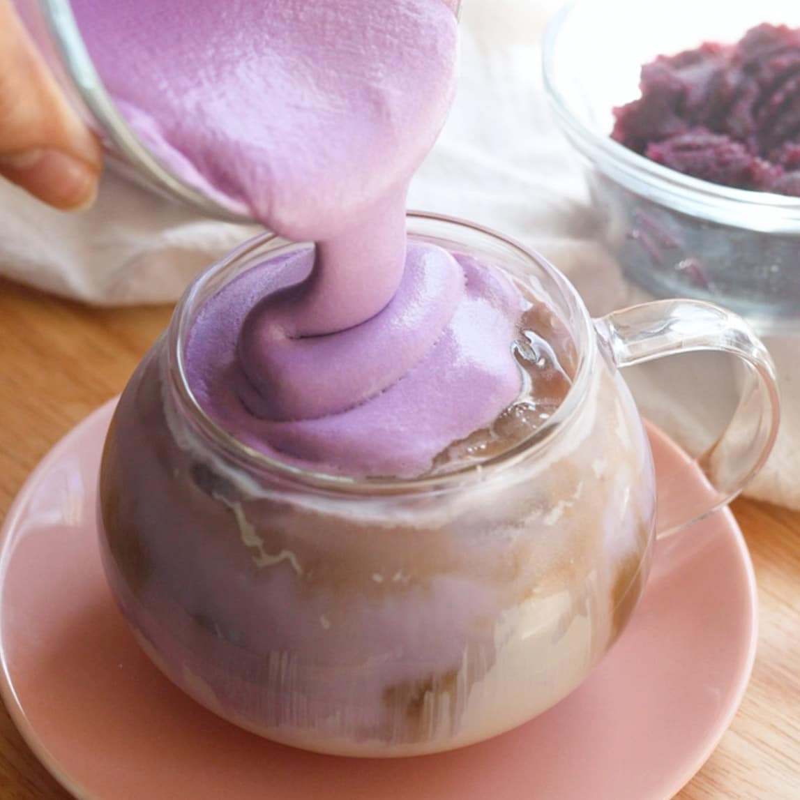 Vibrant purple ube latte with ube cold foam in a glass mug.