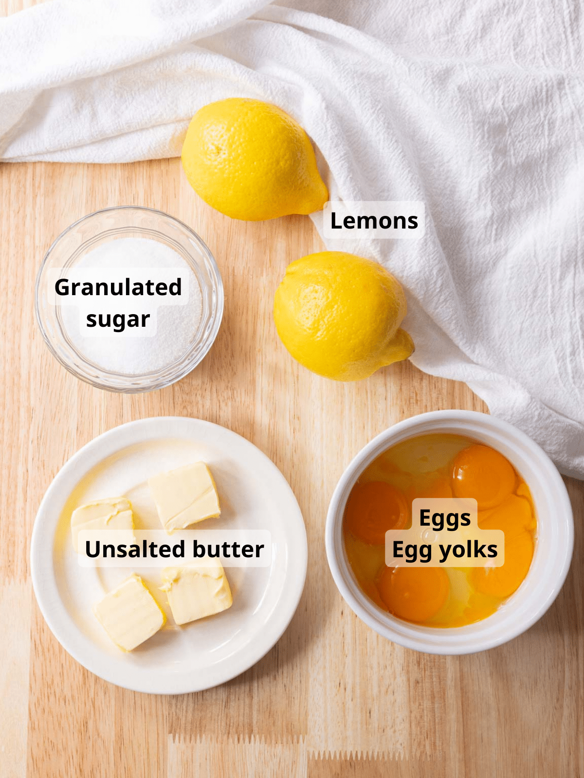 Labeled lemon curd ingredients on a wooden backdrop.