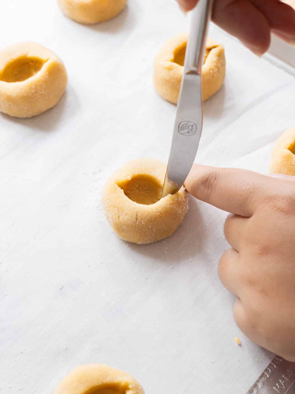 Shaping middle of thumbprint cookie with a knife to make it look like a lemon center.