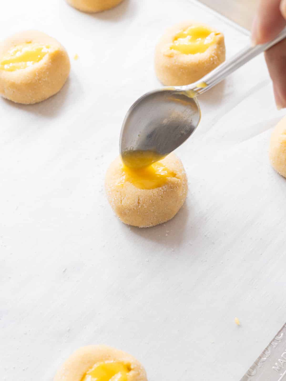 Spooning in lemon curd to the middle of the thumbprint cookie.