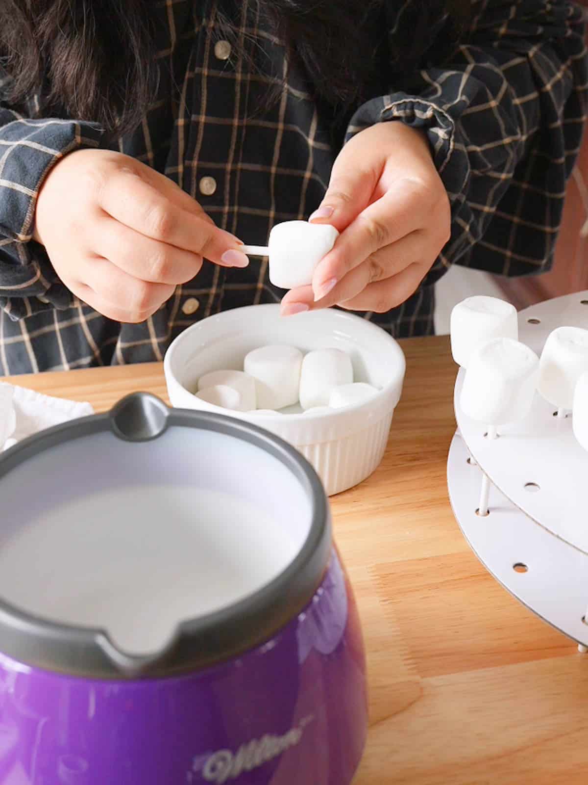 Skewering marshmallow pops with treat sticks.