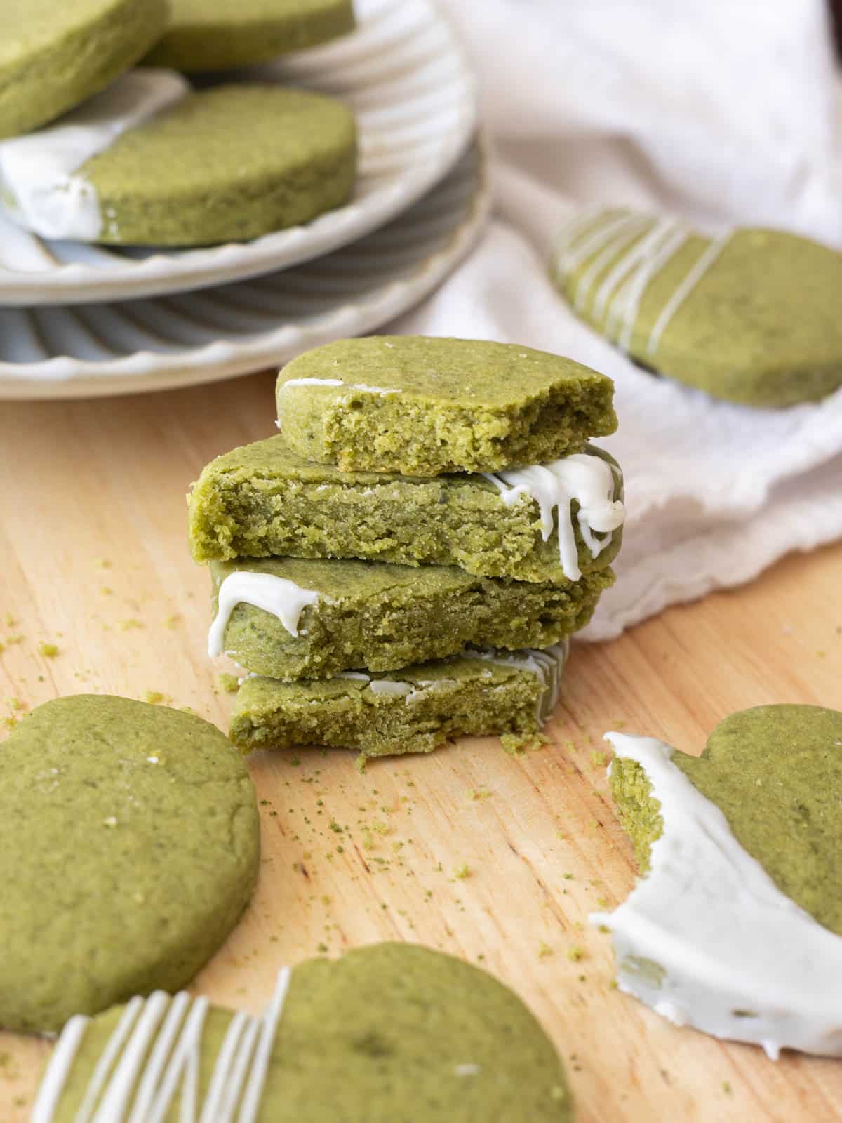 Matcha sugar cookies broken in half, stacked on top of one another with cross section aiming at viewer to show texture.