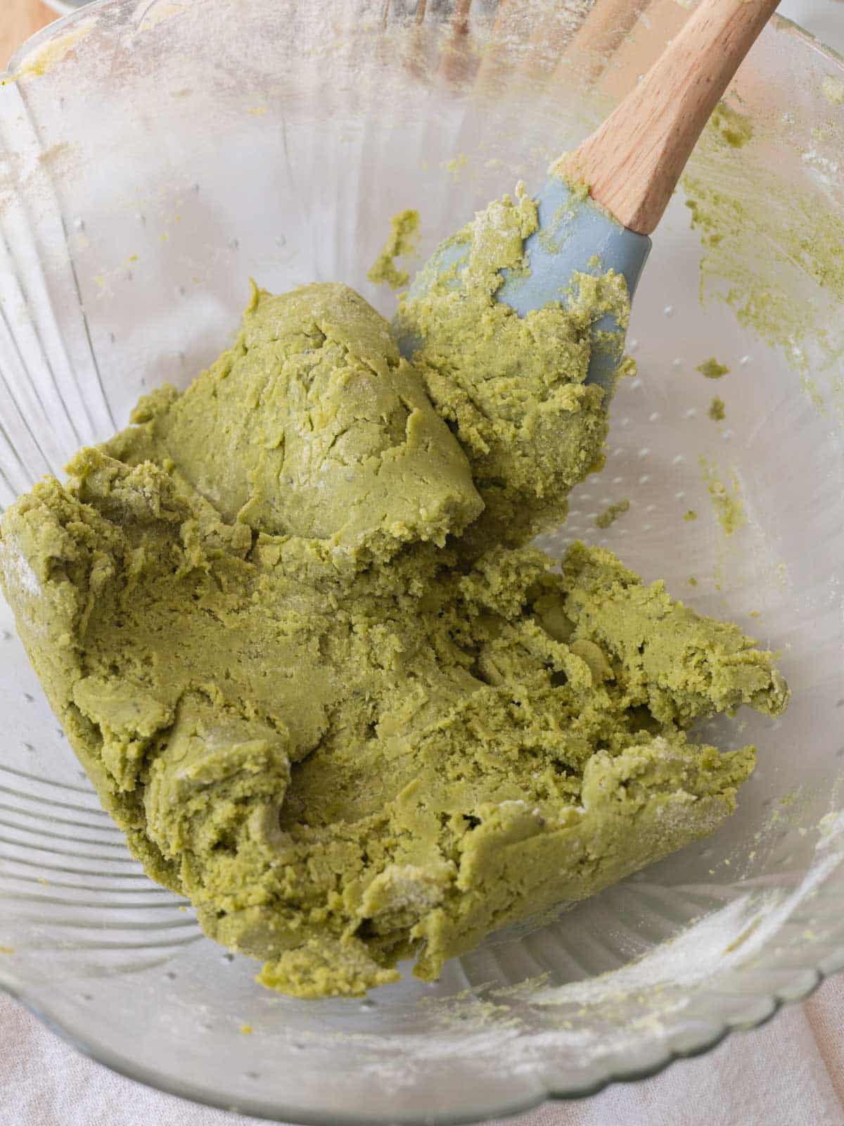 Green matcha cookie dough in glass mixing bowl.