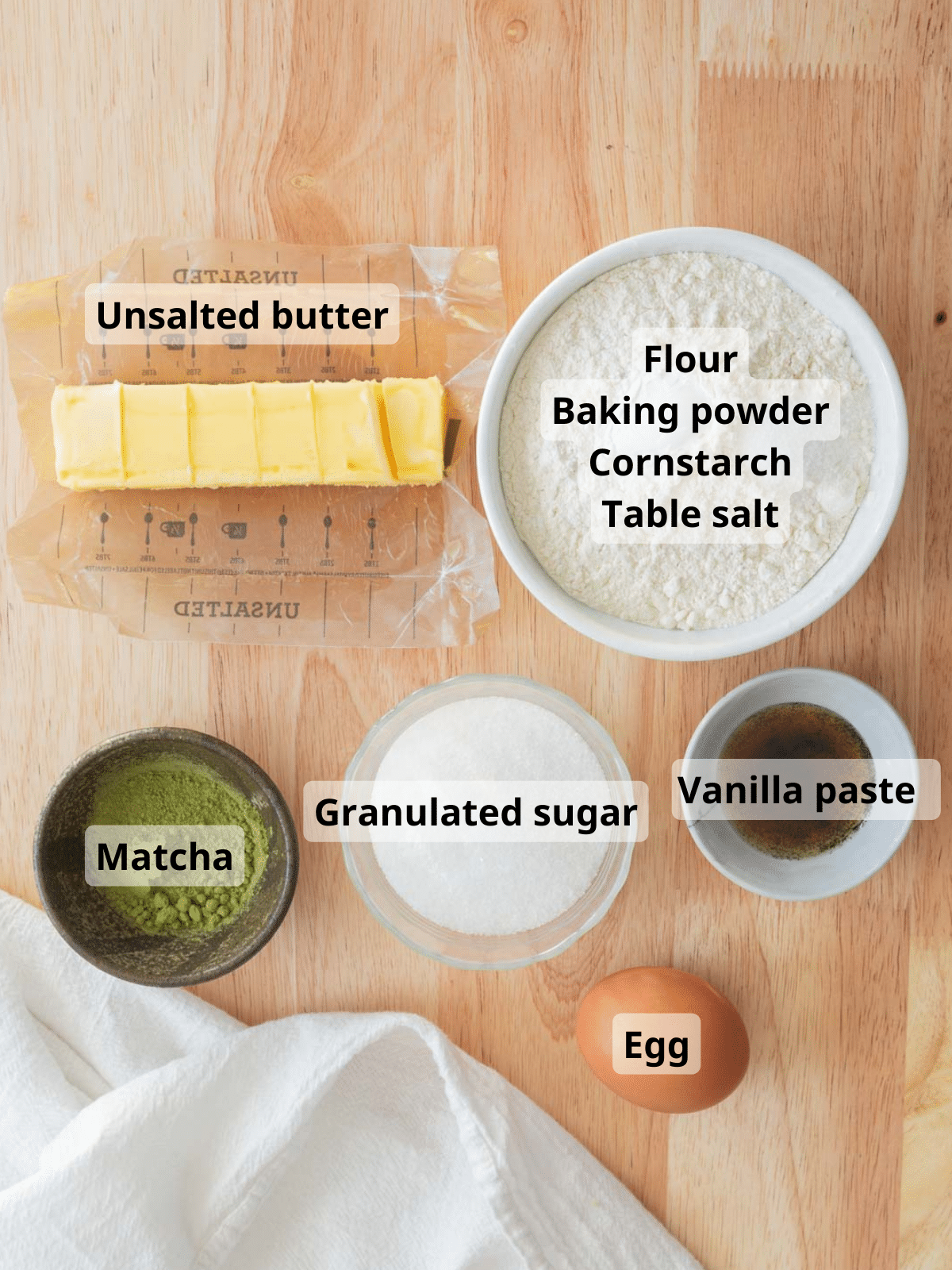 Matcha cutout cookie ingredients with labels on a wooden backdrop.