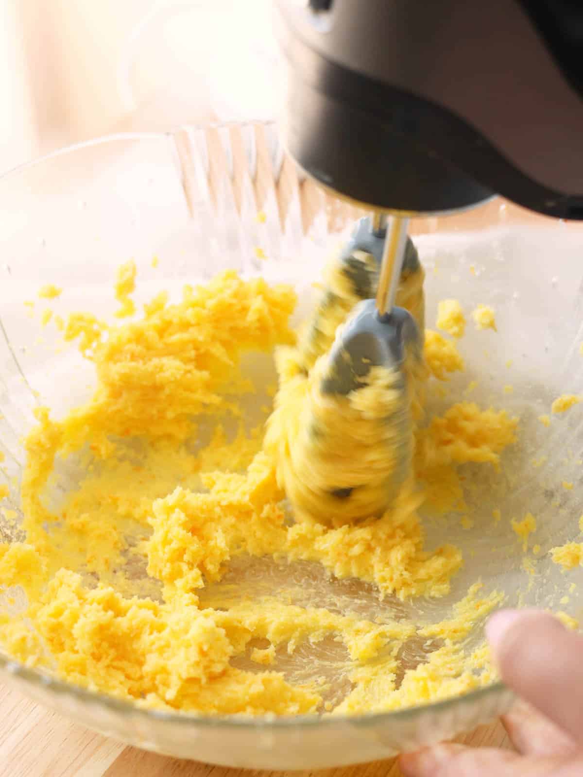 Creaming butter and orange sugar together with hand mixer.