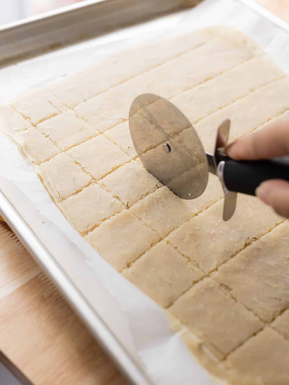 Scoring semi-baked sourdough crackers with pizza cutter.